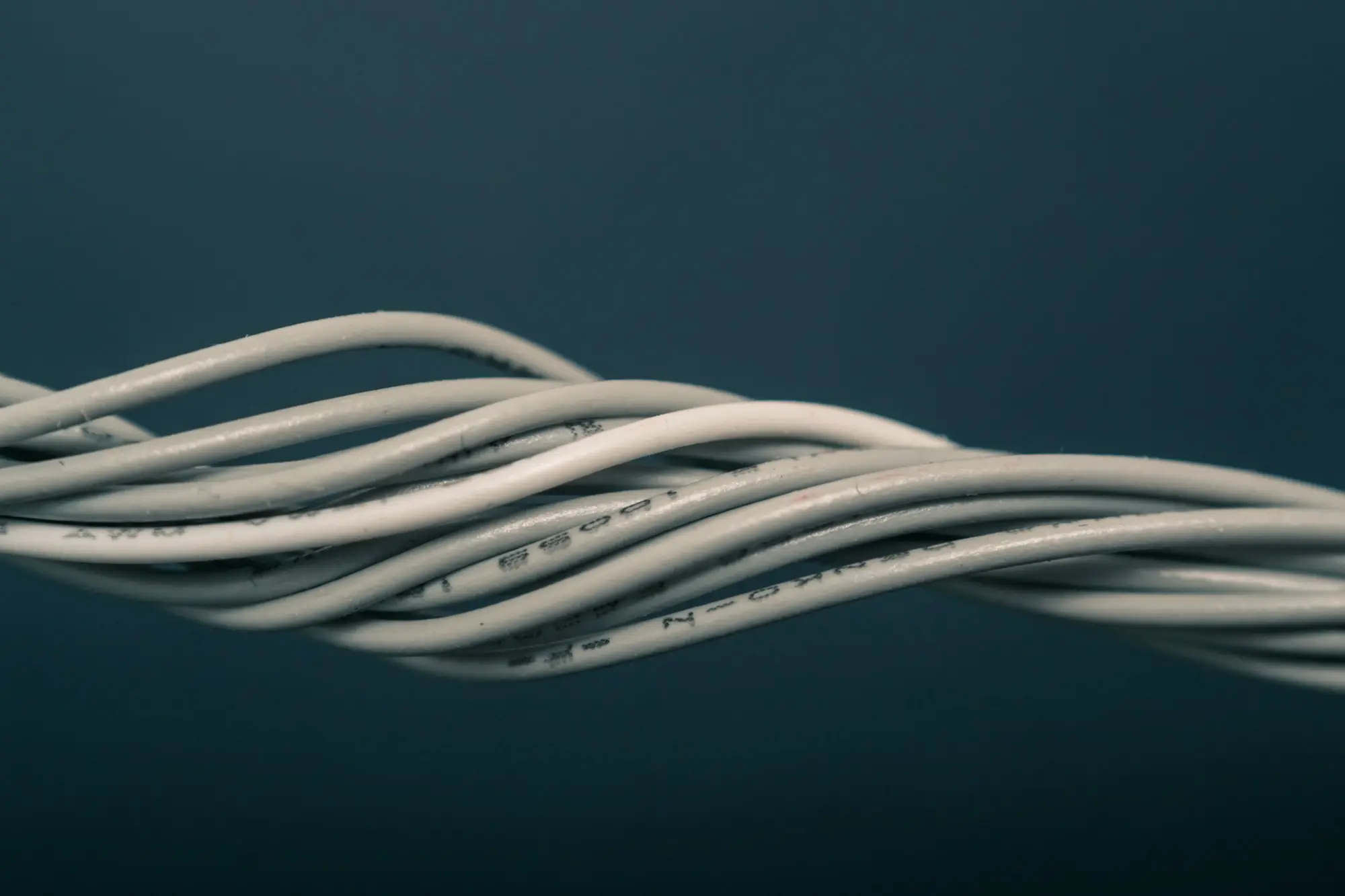 Twisted strands of white insulated cable against a dark background